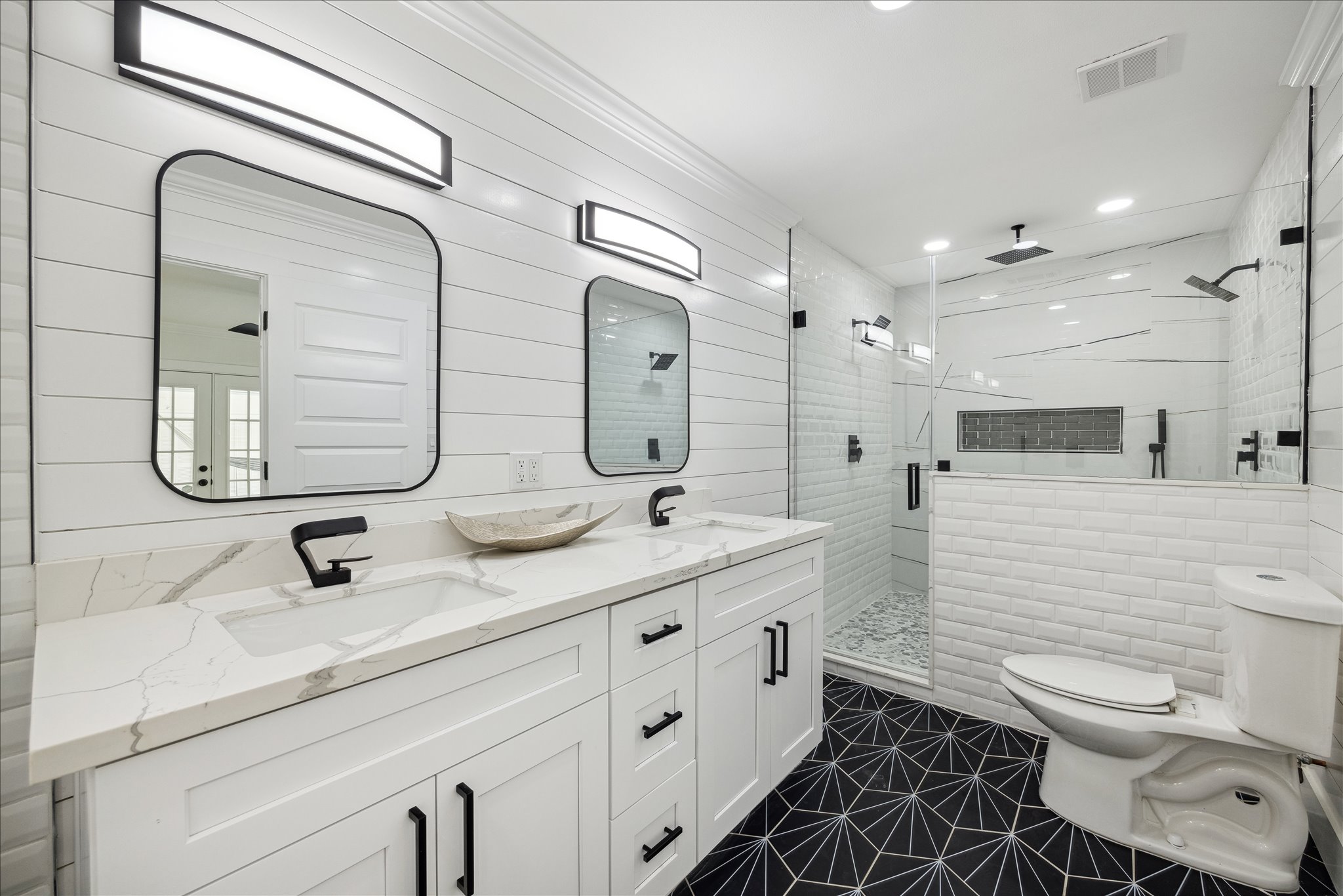 Modern white bathroom remodel with black fixtures and custom shower
